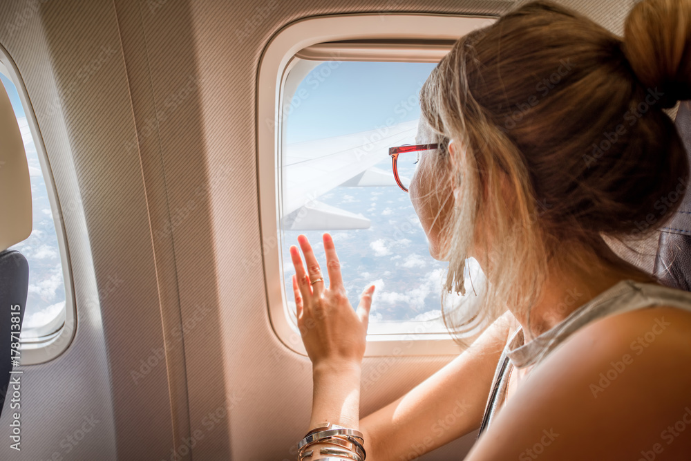 年轻女子坐在飞机上，通过飞机窗户欣赏风景