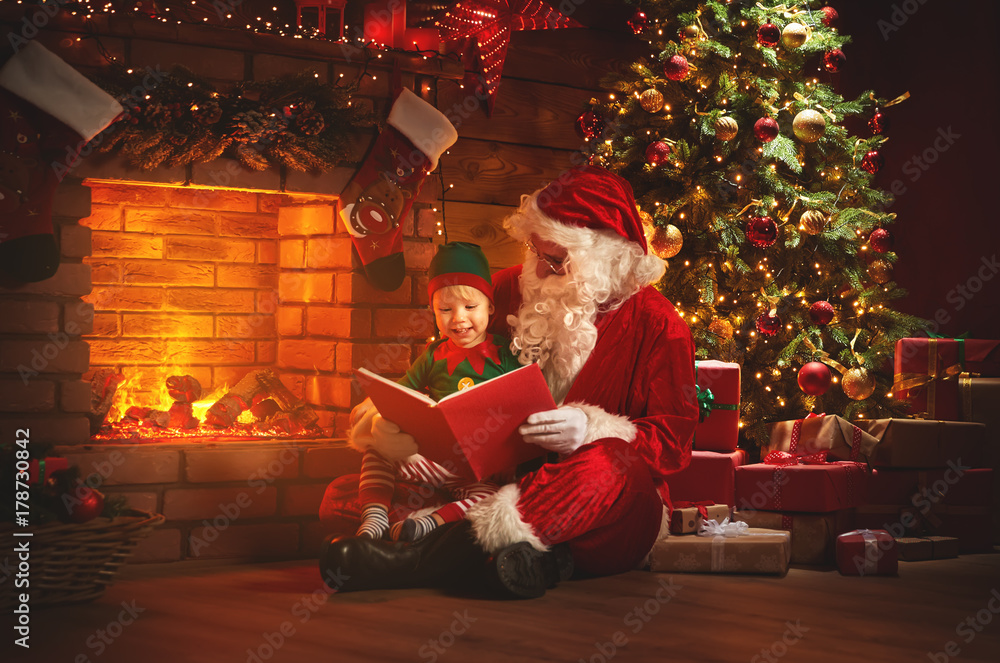 santa claus reads a book to a little elf by Christmas tree