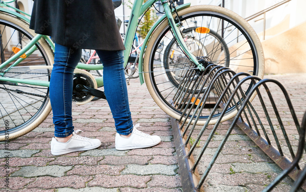 女孩把自行车停在城市的街道上