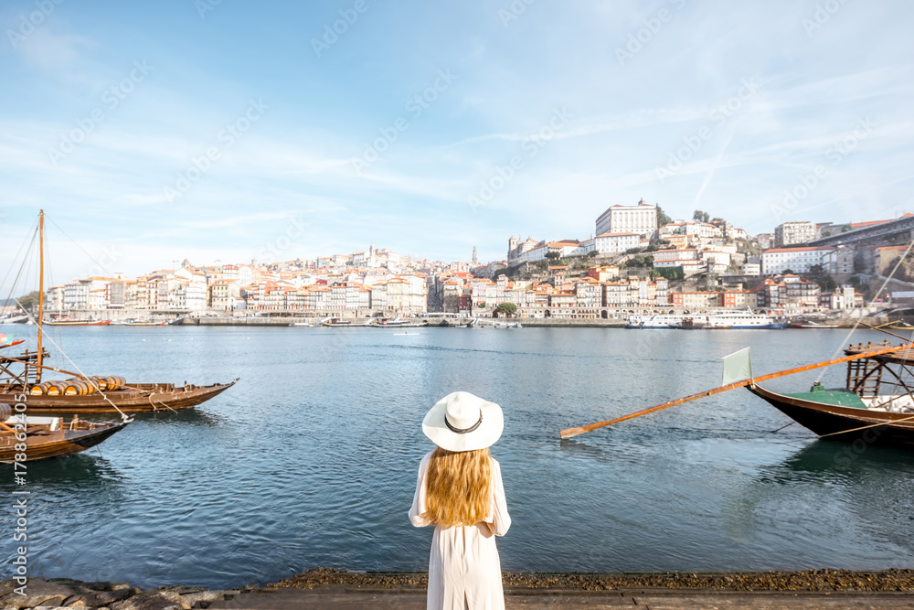 年轻的女性旅行者享受美丽的城市景观杜罗河和传统的葡萄牙船只