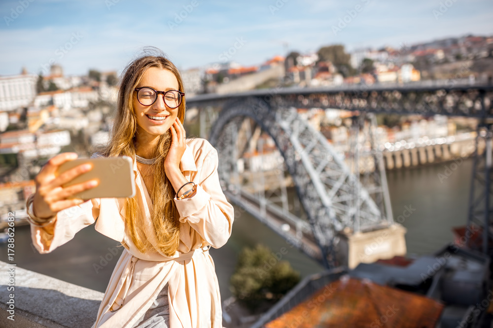 年轻女子在著名桥梁的美丽城市景观背景下用手机自拍