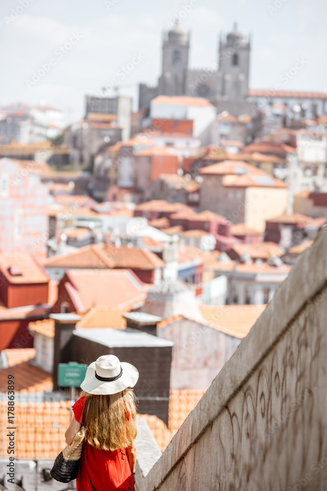 身穿红色连衣裙的年轻女游客在葡萄牙波尔图市的老城区散步