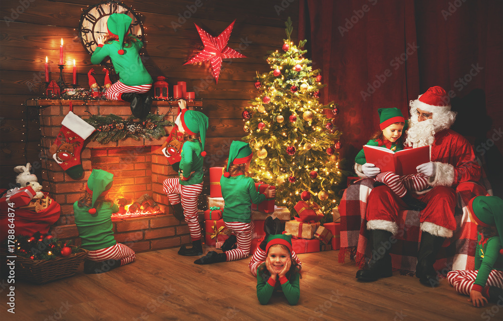 Santa Claus and little elves before Christmas in his house.