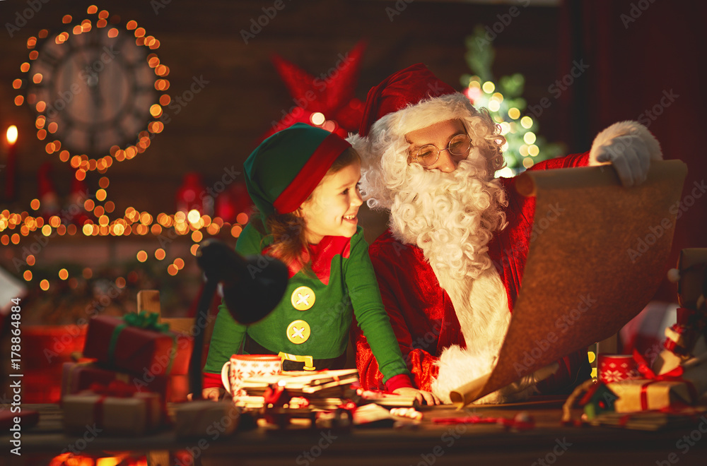 圣诞老人在圣诞树旁给小精灵念好孩子名单