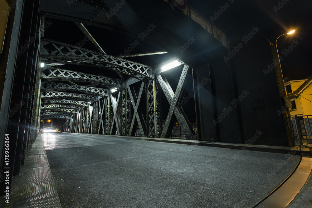 城市桥梁钢结构下的沥青路。汽车灯光下的城市夜景