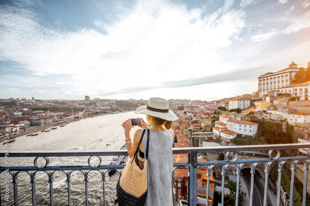年轻的女游客在日落时站在铁桥上欣赏古城美景
