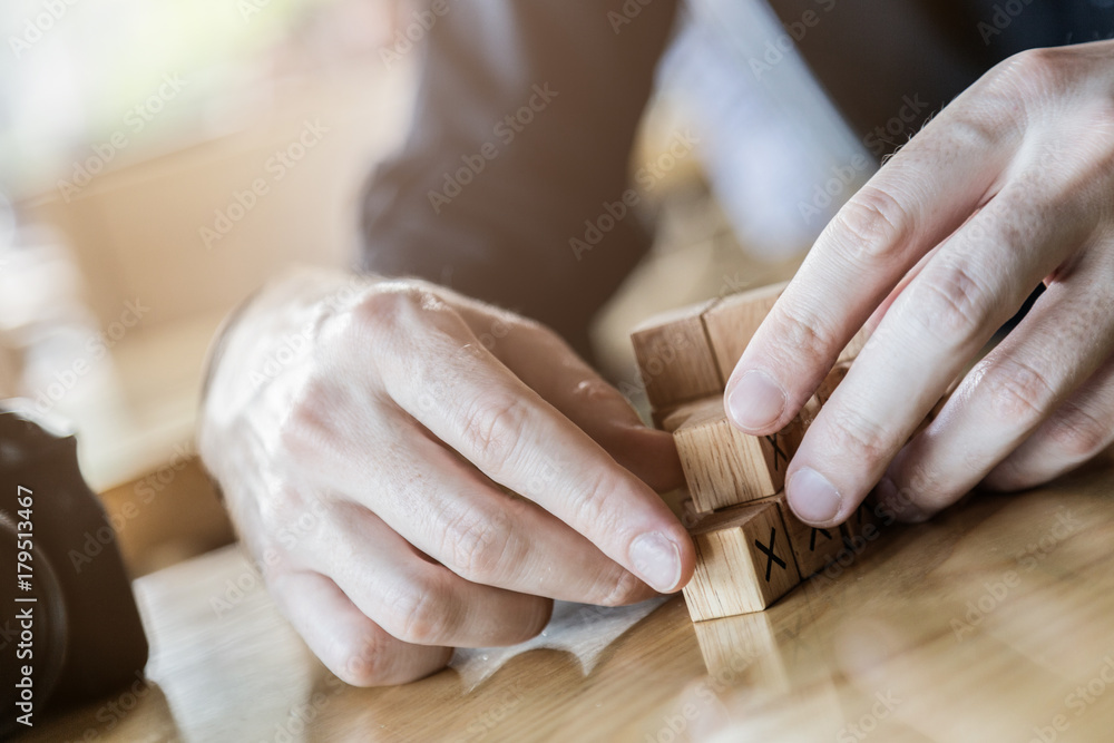 商人试图在木桌上搭建木块，模糊背景创业概念