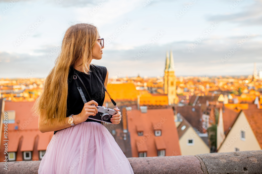 年轻的女性旅行者在日落时坐在相机前欣赏美丽的城市景观i