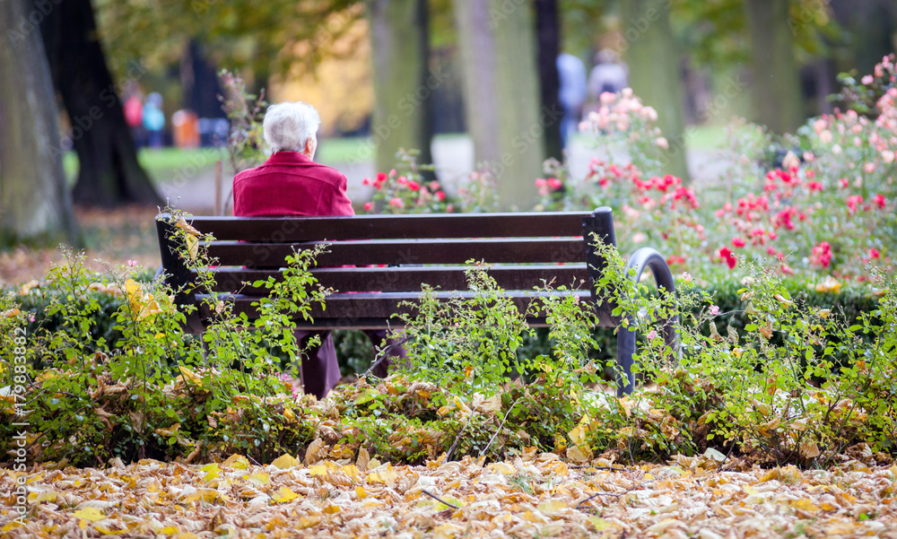 沮丧悲伤的老妇人独自坐在公园的长椅上