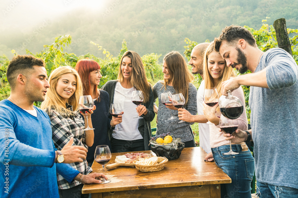 Group of happy friends having fun outdoors drinking red wine - Young people eating local fresh food 