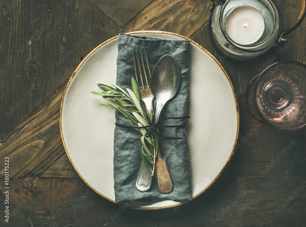 秋季节日餐桌装饰设置。盘子里有灰色亚麻餐巾、叉子和勺子、蜡烛、玻璃a
