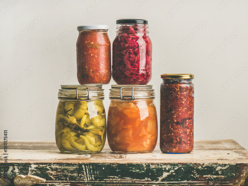 秋季时令腌制或发酵的彩色蔬菜，装在老式厨房抽屉上的玻璃罐里。