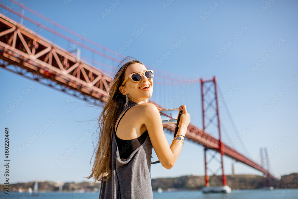 葡萄牙里斯本市拍摄著名铁桥的年轻女性游客