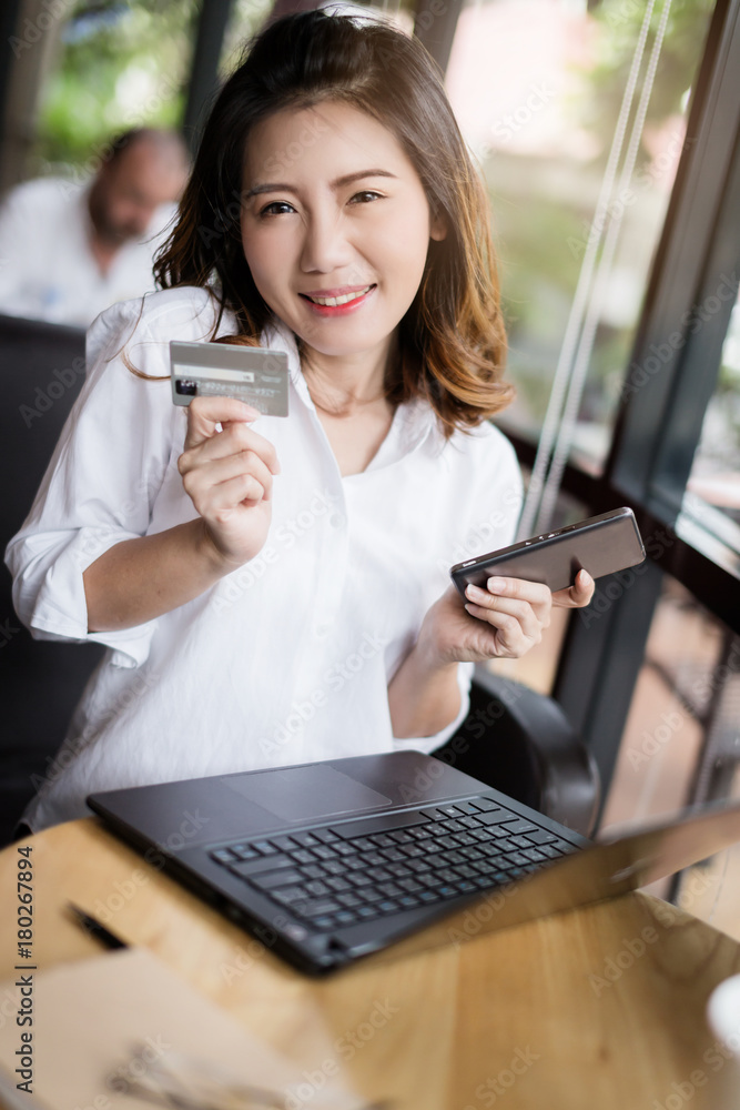 商务亚洲女孩，穿着白衬衫，带信用卡和智能手机，有购物理念