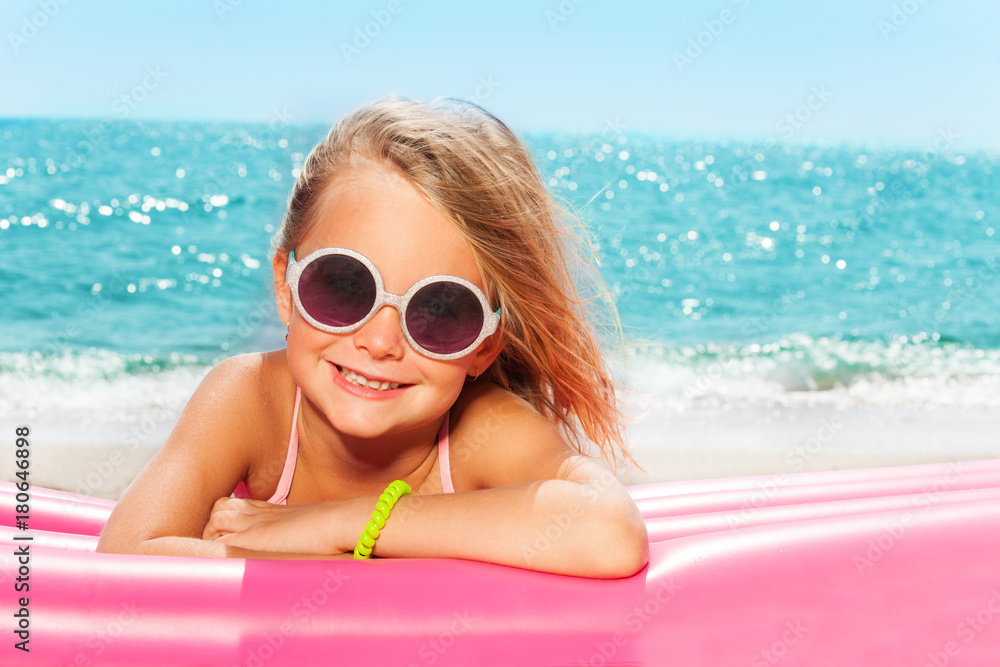 戴着圆形太阳镜在海滩上晒日光浴的可爱女孩