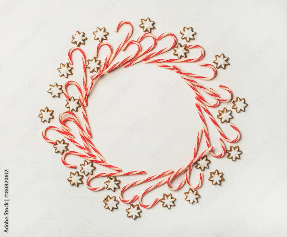 圣诞花环图案由白色背景的甘蔗糖棒和星形糖饼干制成。