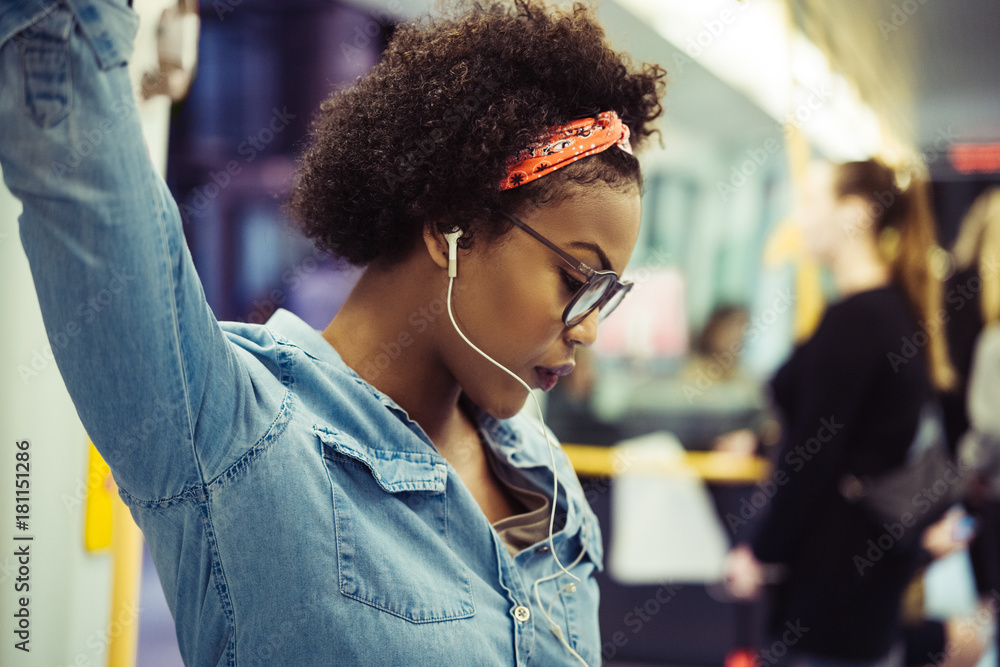 年轻的非洲妇女在地铁上听音乐