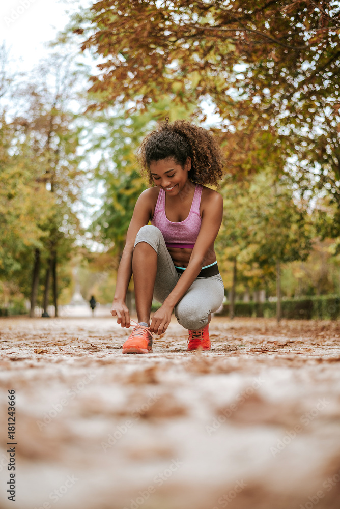 Female sport fitness runner getting ready for jogging outdoors in park.
