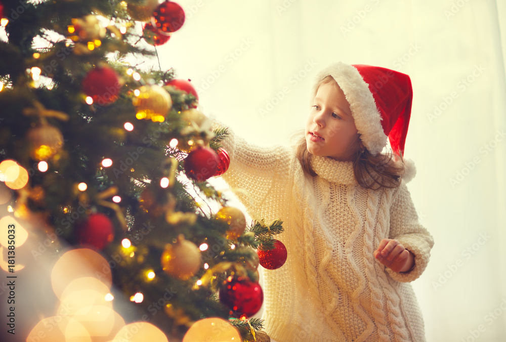 快乐的小女孩装饰的圣诞树。