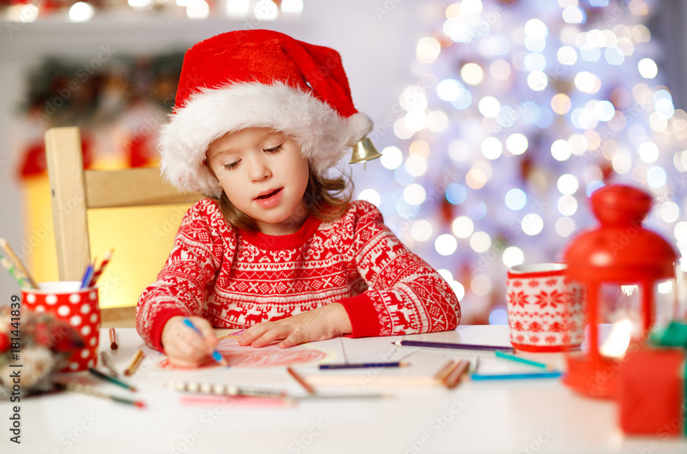 在圣诞树附近给圣诞老人家写信的小女孩