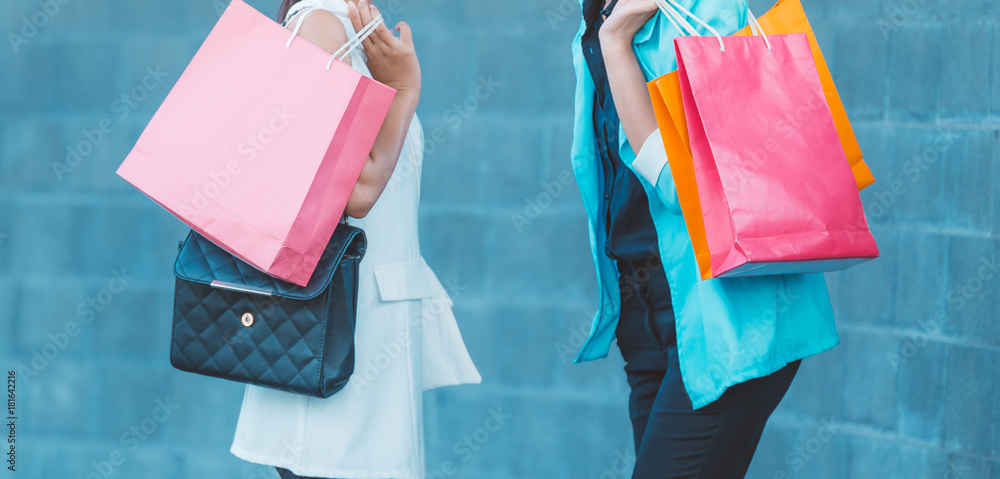 销售、消费主义和人的概念——快乐的年轻女性在城市的商店里看着购物袋。