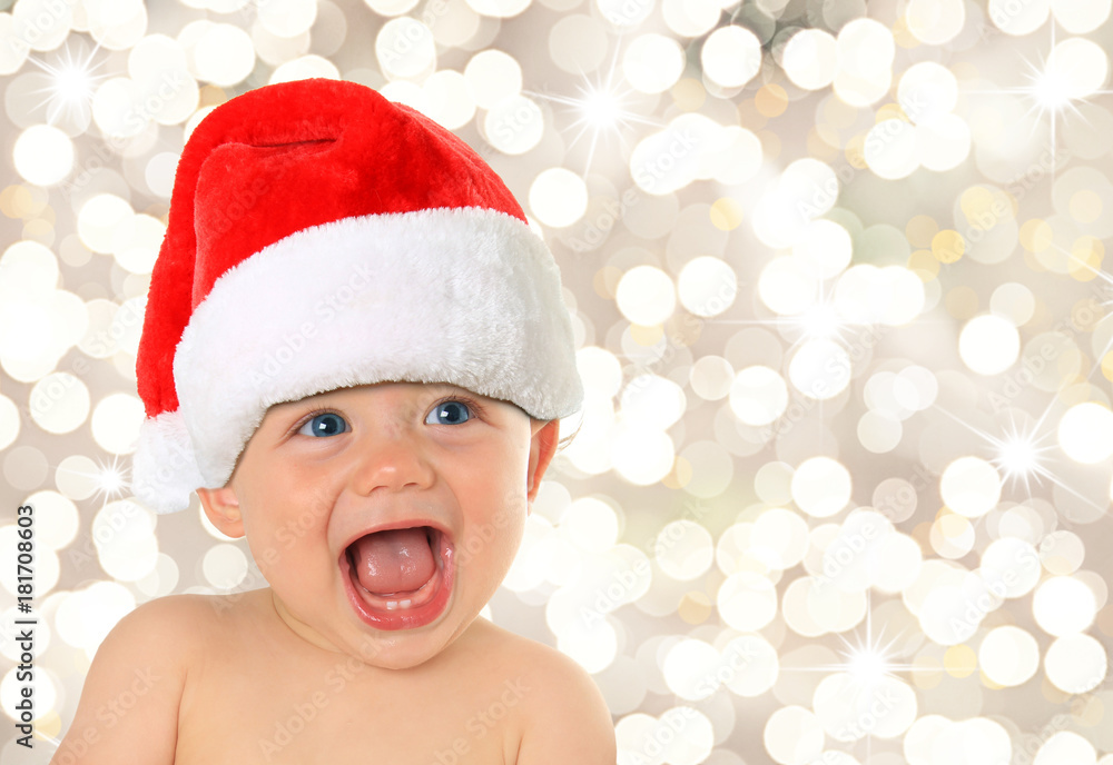 快乐的十个月大的蓝眼睛男婴戴着圣诞老人的帽子。