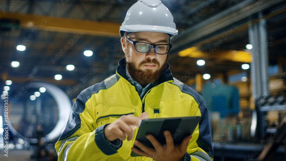 Industrial Engineer in Hard Hat Wearing Safety Jacket Uses Touchscreen Tablet Computer. He Works at 