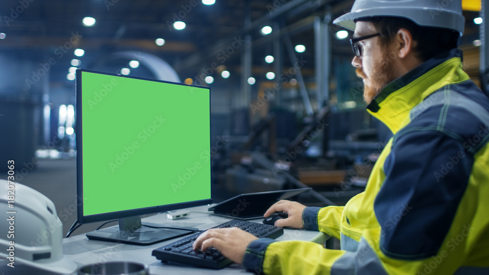 重工业工厂内部工业工程师用绿色模型在个人电脑上工作