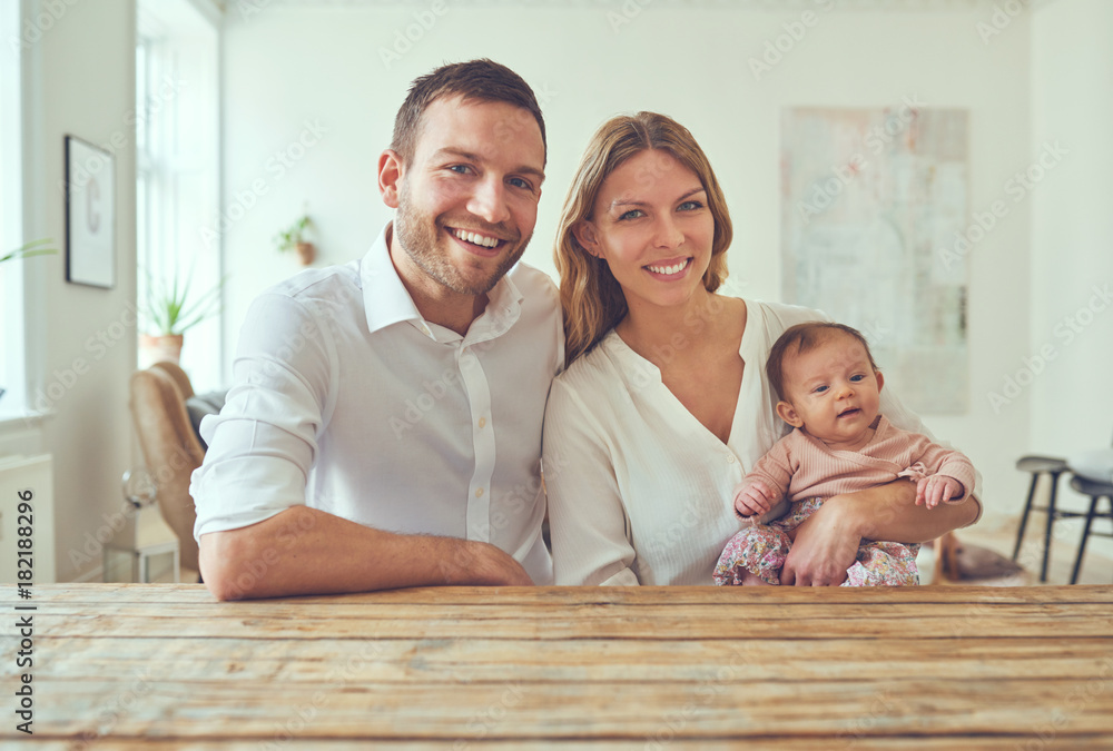 微笑的年轻夫妇和家里的女婴坐在一起