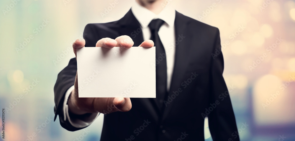Businessman with a blank business card on pink and blue abstract light background