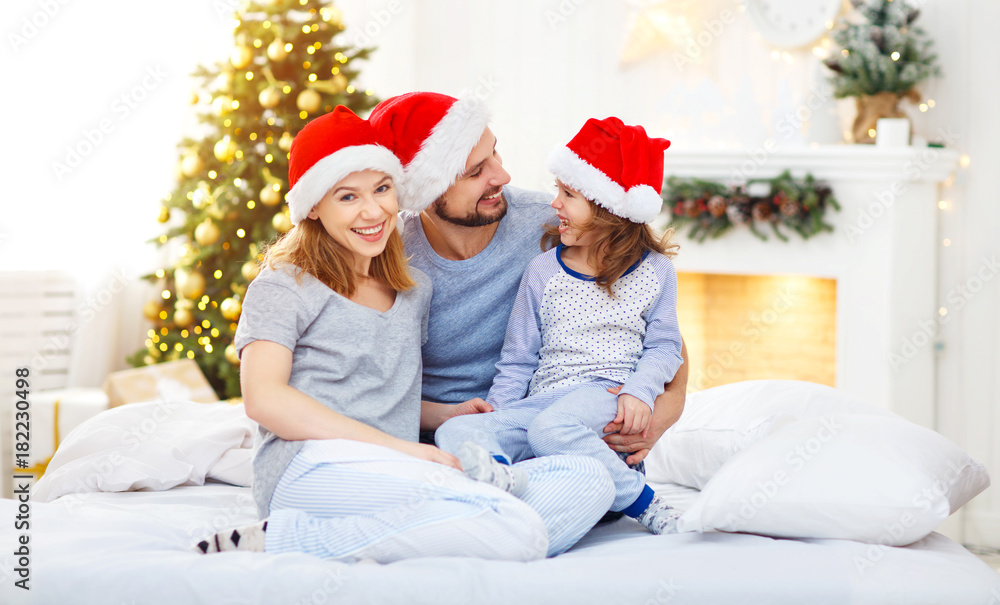 快乐的家庭母亲父亲和孩子在圣诞节早上躺在床上