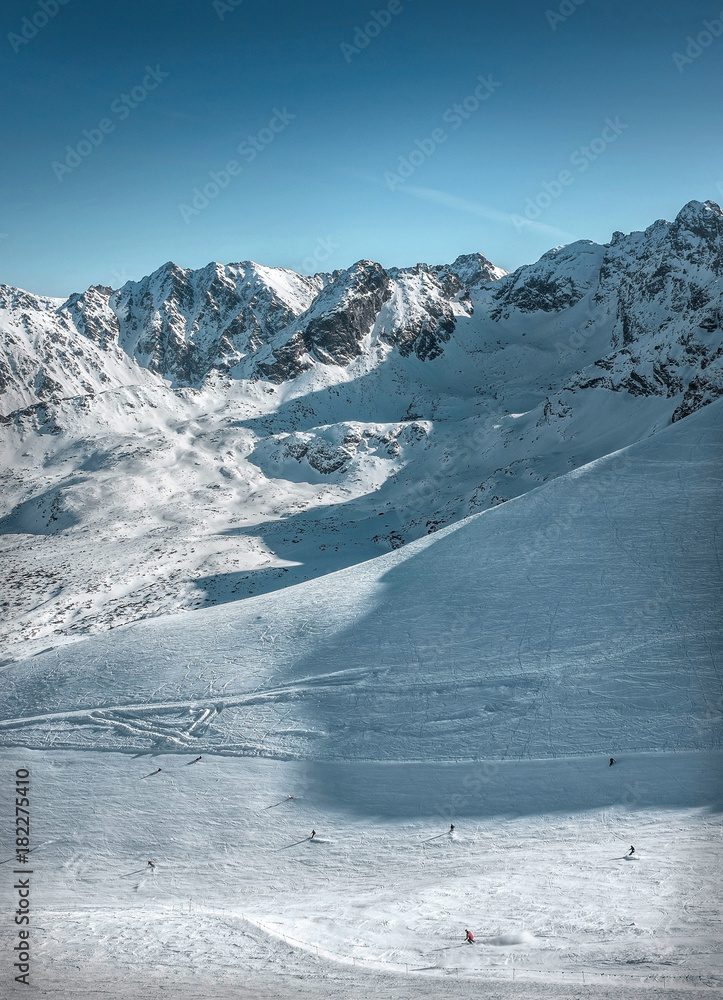 阳光明媚的日子里，滑雪爱好者在蓝天下欣赏美丽的山景