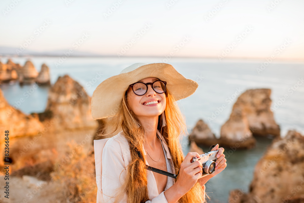 一位年轻女子的肖像，带着相机，在苏期间欣赏岩石海岸线的美景