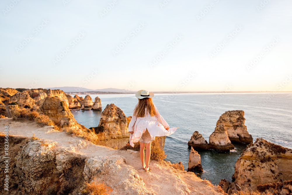 波图加南部拉各斯日出时，一名女子在岩石海岸线上欣赏美景