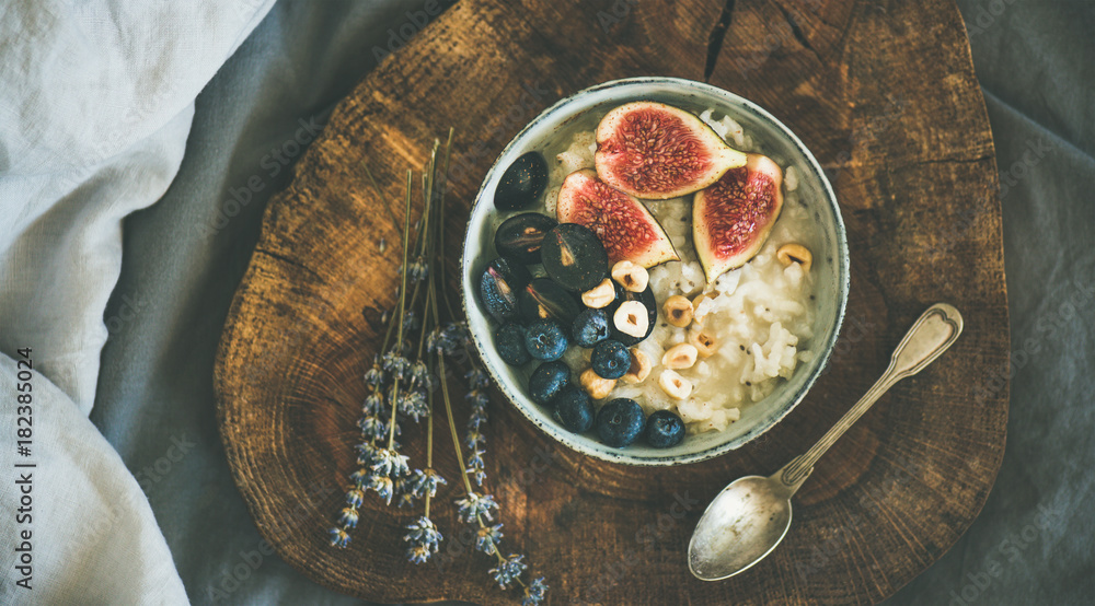 健康的冬季早餐。米饭椰子粥配无花果、浆果和榛子，碗里放在乡村