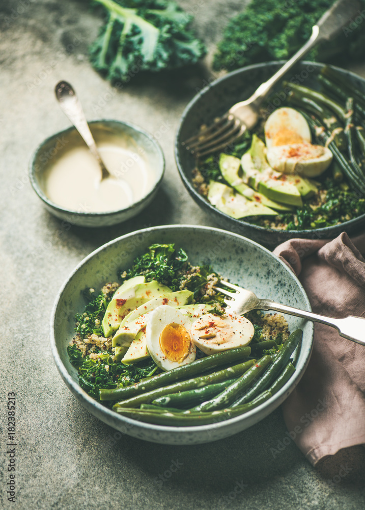 Healthy vegetarian breakfast bowls. Quinoa, kale, green beans, avocado, egg and creamy tahini dressi