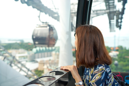 亚洲女孩在缆车上看美丽的风景。女子乘坐缆车