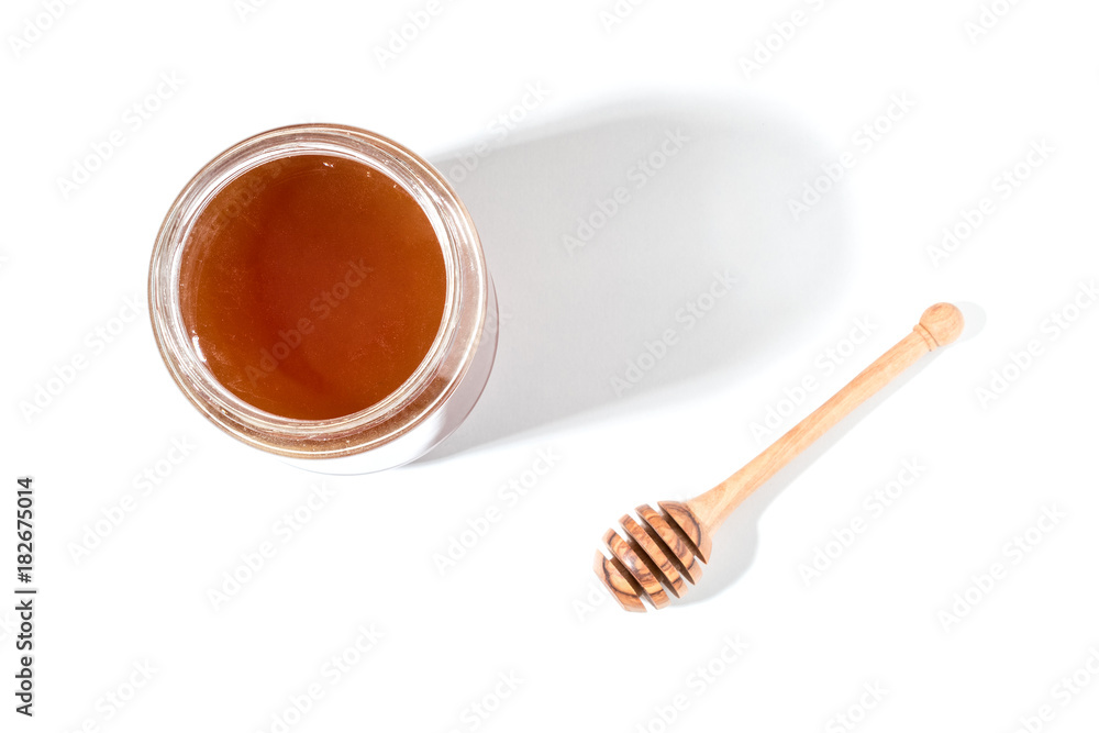 蜂蜜勺和白底罐子里的蜂蜜。