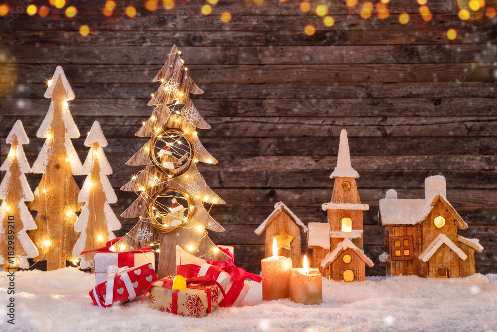 节日背景，有发光的圣诞树、礼物和木制村庄。