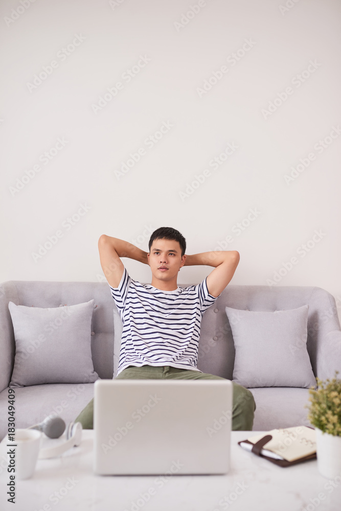 Young man looking up while working on laptop at home