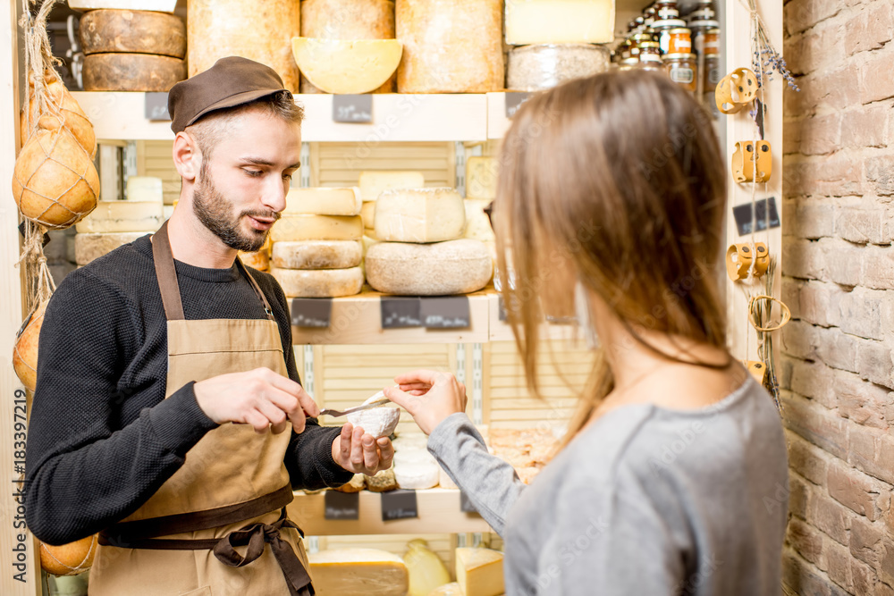 售货员和一位女顾客在食品店挑选奶酪