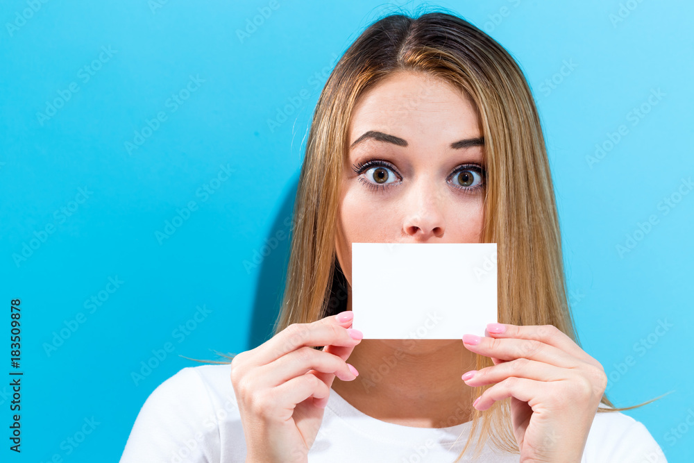 Woman holding a blank message card in front of her face