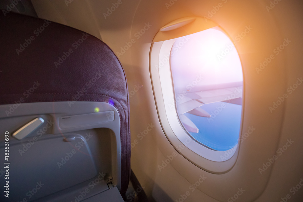 从乘客座位上看到，飞机在壮观的日落光线下在云层上方飞行。