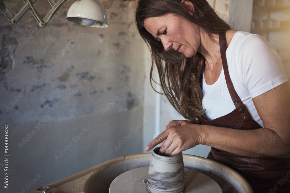 女性工匠在她的陶器工作室创造性地雕刻粘土