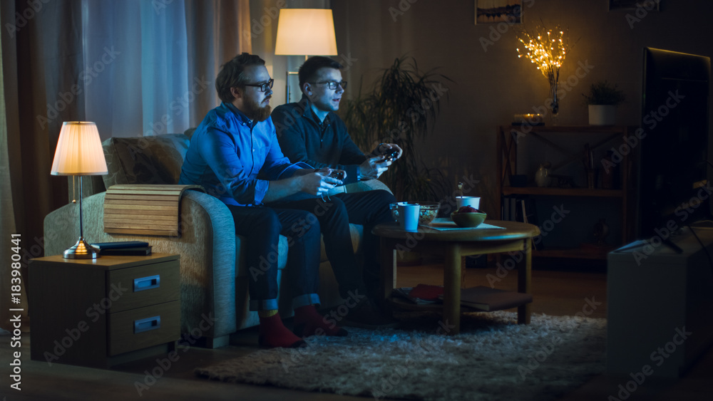 晚上两个朋友坐在客厅的沙发上玩竞技视频G