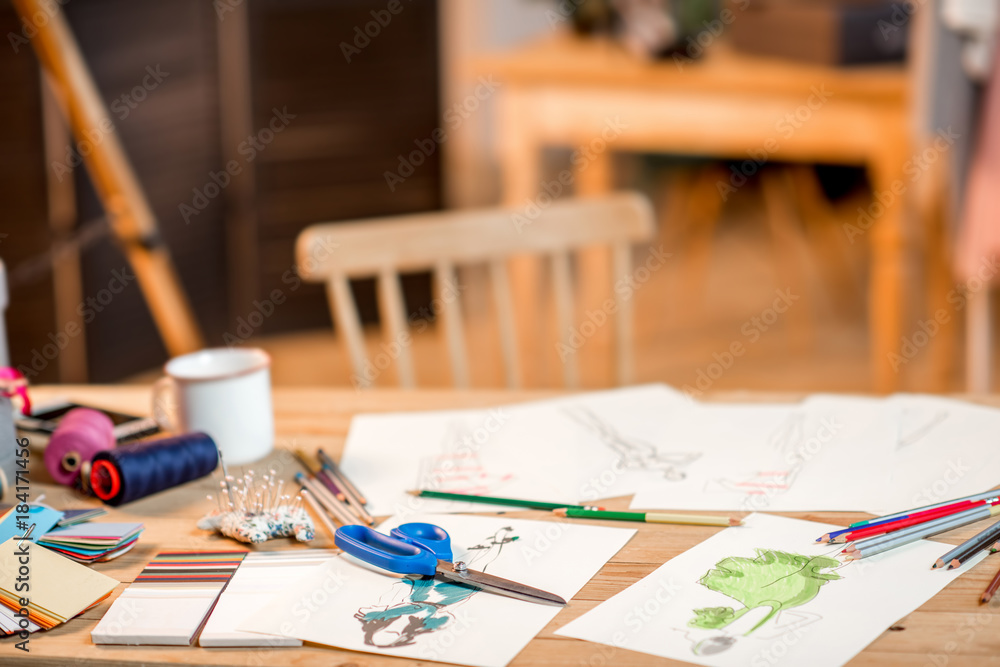 时装设计师工作场所，桌子上有裁剪工具和图纸