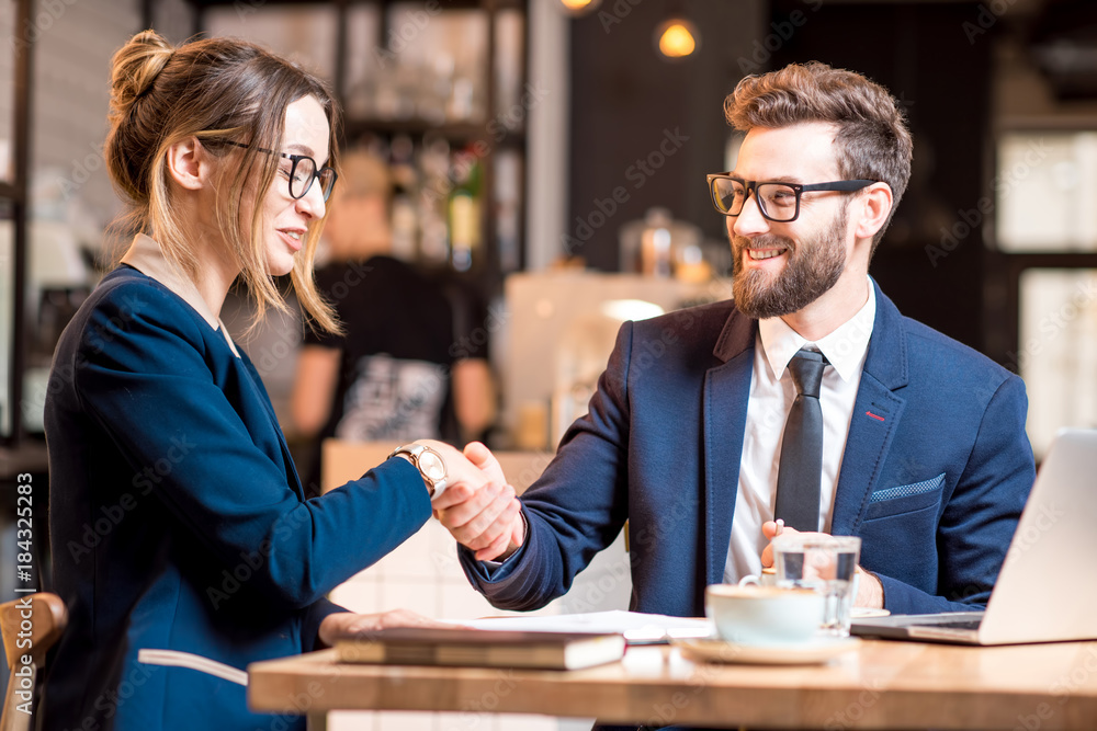 商务情侣在咖啡馆共进午餐时握手