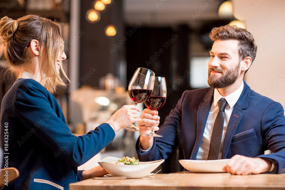 快乐的商务情侣在餐厅碰杯，晚餐时交谈