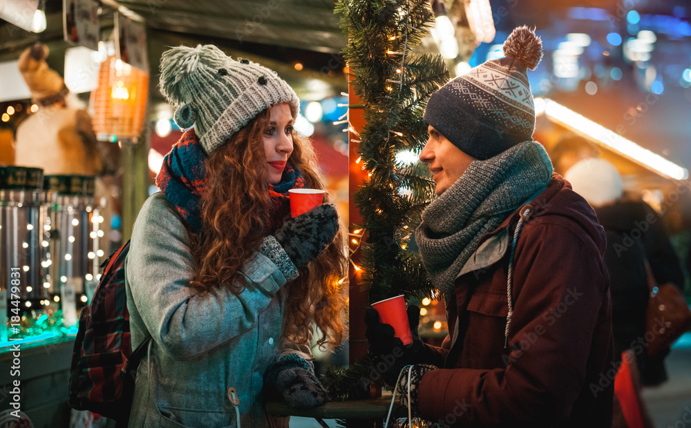 晚上的圣诞市场餐厅，情侣在童话般的环境中享用热饮
