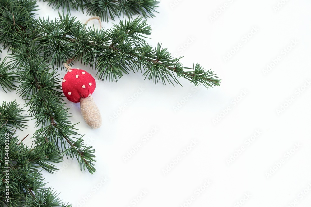 近距离观察雪松树枝和白色背景上的圣诞装饰蘑菇。圣诞背景